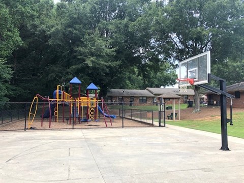 a childrens park with a playground and a basketball court